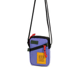 Topo Designs mini shoulder bag, a compact crossbody bag with adjustable strap and durable fabric, shown in a natural outdoor setting.