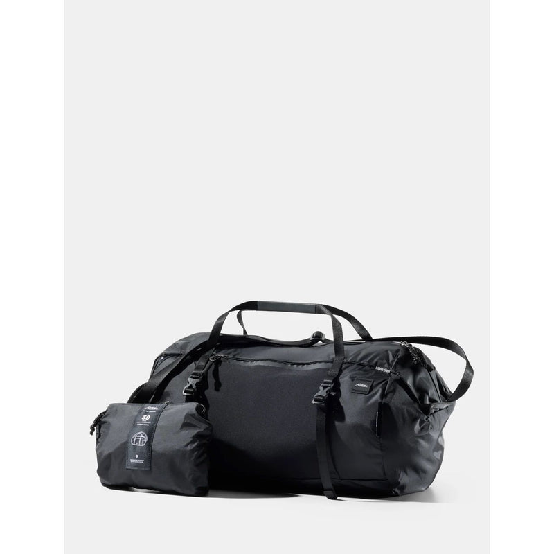 Black Matador 30L packable duffel bag laid flat, showing its compact, lightweight design and durable material.