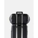 Black Matador 30L packable duffel bag folded and partially unfolded, showing its compact design and durable material.