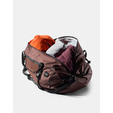 Red 30L Matador packable duffel bag folded and partially unrolled, showing compact design and durable material.