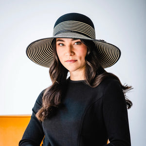 Black Marseille UPF 50+ packable hat by Wallaroo Hat Company shown in a lifestyle setting with wide brim and sun protection features.