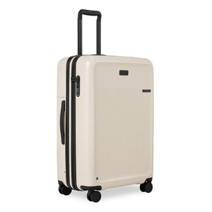 Briggs & Riley Sympatico large expandable checked luggage spinner with four wheels and sturdy handle, viewed from an angle.