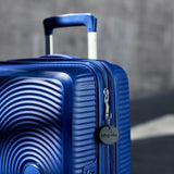 Chipolo ONE Spot Bluetooth tracker attached to a luggage handle for Apple devices, showing its compact design and keyring attachment.