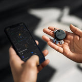 Chipolo ONE Spot Bluetooth tracker attached to a smartphone, showing the Chipolo app interface on a smartphone screen.