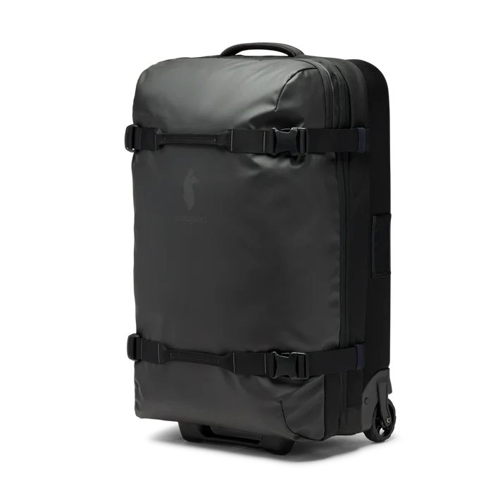 Cotopaxi 65L Roller Bag checked luggage with durable wheels and handle, black color, designed for travel and easy rolling.
