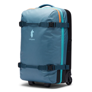 Cotopaxi 65L roller checked luggage bag with durable hard shell and telescoping handle, suitable for travel.