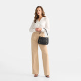 Hammitt Bryant Med crossbody bag in black brushed gold leather with red zipper and metal hardware, stylish and compact.