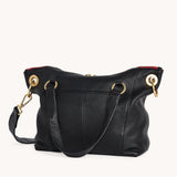 Black Hammitt Daniel Med purse with brushed gold accents and red zipper, showcasing a sleek, elegant design.