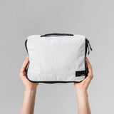 Set of three white Matador packing cubes neatly stacked, ideal for organizing clothes and travel essentials in luggage.
