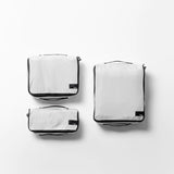 Set of four white packing cubes in various sizes from Matador's 3-pack packing cube set for organized travel storage.