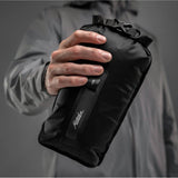 Black Matador Flatpak dry bag 2L with roll-top closure, designed for waterproof storage of small essentials during outdoor activities.