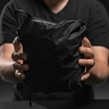 Matador Freefly 30L packable duffle bag in black, showing compact design and rolled-up form for travel storage.