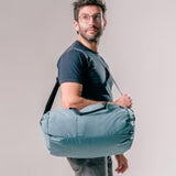 Matador Refraction packable duffle bag in gray fabric, showing compact design and adjustable shoulder strap.