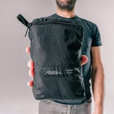 Matador Refraction packable duffle bag in black, showing its compact size and durable nylon material for travel and outdoor use.