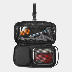 Open small Nomatic toiletry bag showing organized interior with multiple compartments and black fabric for travel storage.