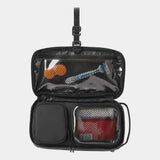 Open small Nomatic toiletry bag showing organized interior with multiple compartments and black fabric for travel storage.