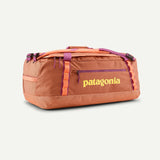 Patagonia black 55L Black Hole duffel bag with peach accents, showing durable fabric and sturdy handles for travel and storage.