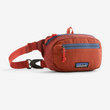 Patagonia Ultralight Black Hole Mini Hip Pack 1L in patchwork Subtidal Blue, compact pack with adjustable strap and logo patch.