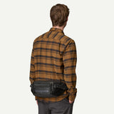 Patagonia Black Hole® waist pack in shiny black with adjustable strap, compact 5L size, ideal for carrying essentials.