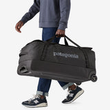 Patagonia Black Hole® Matte Wheeled Duffel 100L in black, showing sturdy wheels and spacious design for travel storage.