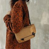 Peak Design Field Pouch V2 in coyote color, shown with outdoor gear and accessories in a lifestyle setting.