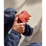 Secrid Miniwallet Original in orange with a lifestyle background, showcasing a compact leather wallet with card slots.