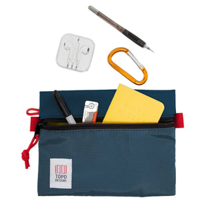 Open navy Topo Designs accessory bag with organized contents, showcasing compact storage for everyday essentials.