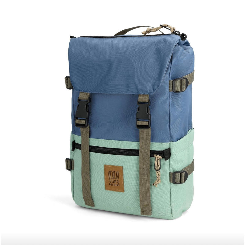 Topo Designs Rover Pack Classic backpack with multiple compartments and padded straps, shown in a natural outdoor setting.