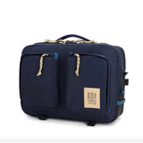 Topo Designs Global Briefcase showing durable black canvas and leather accents, with a top handle and adjustable shoulder strap.