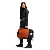 Topo Designs Global Travel Bag roller carry-on luggage in black and burgundy with durable wheels and sleek design.