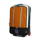 Topo Designs Global Travel Bag Roller carry-on luggage in pond blue and spice, shown from side view with wheels and handle.
