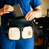 Topo Designs Block Bag crossbody bag in durable fabric with adjustable strap, featuring front pockets and top zipper closure.