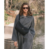 Black Tumi Voyageur Alabama Crossbody Sling with gold accents, featuring adjustable strap and compact, stylish design.