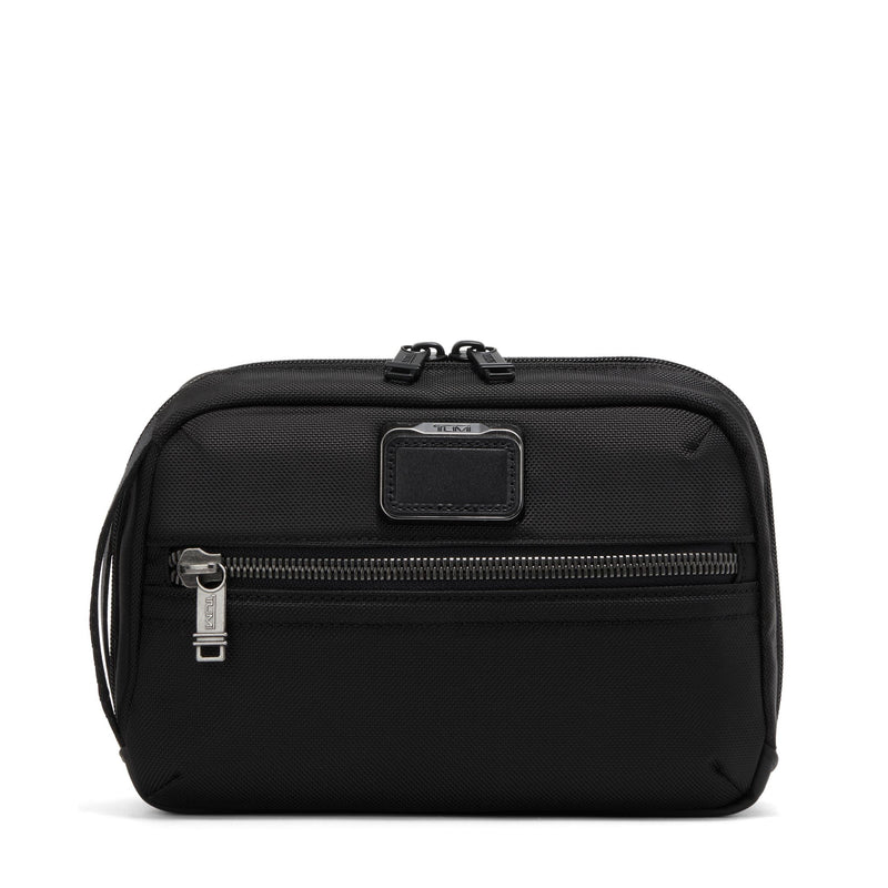 Black Tumi Alpha Bravo Response travel kit with multiple compartments and zippers for organized toiletry storage.