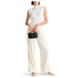 Black Tumi Voyageur Lex small train case crossbody bag with gold accents, compact design, and adjustable strap.