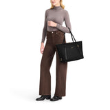 Black Tumi Voyageur Q Tote bag with gold accents, showcasing a spacious design and sturdy handles for versatile use.