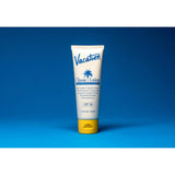 Bottle of Vacation Classic Lotion SPF 30 sunscreen with lotion texture, featuring a white cap and label, on a clean background.