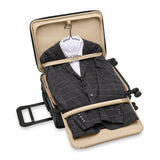 Briggs & Riley Baseline Essential carry-on spinner luggage in blue with four wheels and telescoping handle, ready for travel.