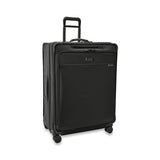 Briggs & Riley Baseline extra large expandable checked luggage spinner with blue exterior and four wheels on smooth airport surface