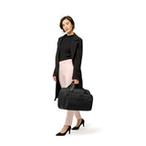 Briggs & Riley Baseline expandable cabin bag, black duffel with wheels and handles, showing front view and zip compartments.