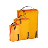 Eagle Creek PACK-IT Isolate Cube Set XS, S, M for organizing clothes and accessories in luggage, shown stacked in a suitcase.