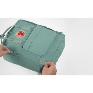 Fjallraven Kanken backpack in frost green with top handle, front zip pocket, and adjustable shoulder straps.