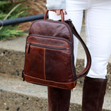 Jack Georges Voyager small backpack in brown leather, showing a lifestyle scene with the backpack outdoors.