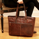 Jack Georges Voyager business tote bag in brown leather, featuring multiple compartments and sturdy handles, displayed in lifestyle setting.