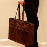 Jack Georges Voyager business tote bag in brown with spacious interior and leather handles, shown in a lifestyle setting.
