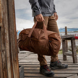 Matador Transit30 duffle bag in coyote color with outdoor gear and travel accessories, showcasing its compact and durable design.