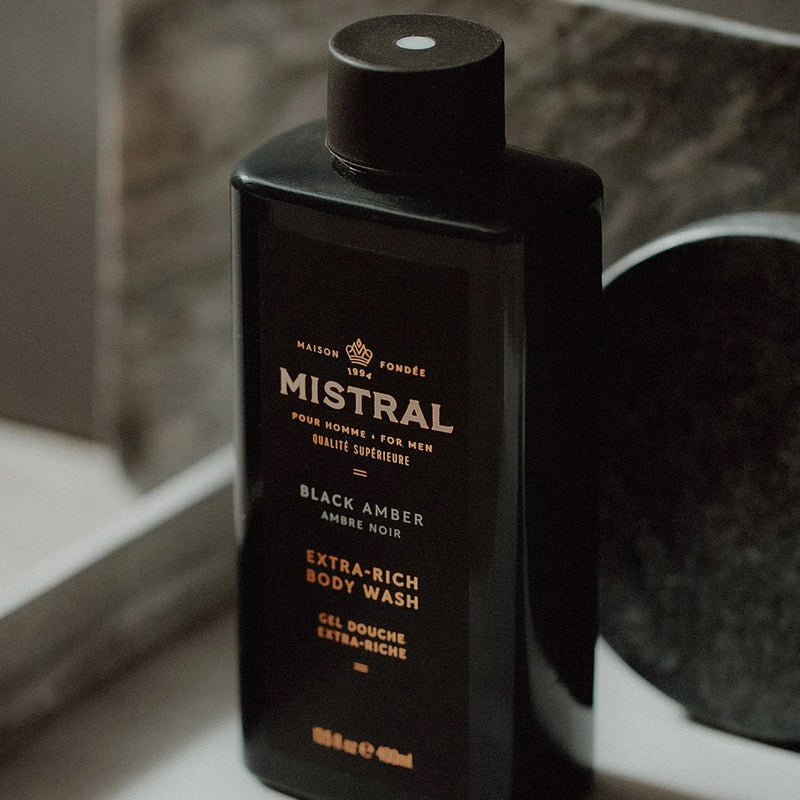 Men's Body Wash by Mistral featuring black amber scent, clear bottle with black cap and sleek design.