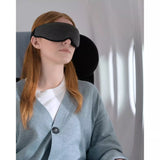 Dark night Ostrichpillow eye mask resting on a plane seat, designed for comfortable sleep during travel.
