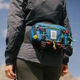 Light beige Topo Designs Subalpine Hip Pack waist pack with adjustable strap and zippered pocket, shown on white background.